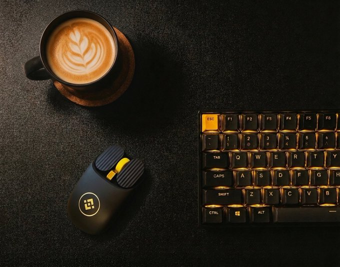 A coffee cup with latte art, an ergonomic mouse, and a backlit mechanical keyboard sit arranged on a dark textured surface, setting the scene for a productive work session to close out August.
