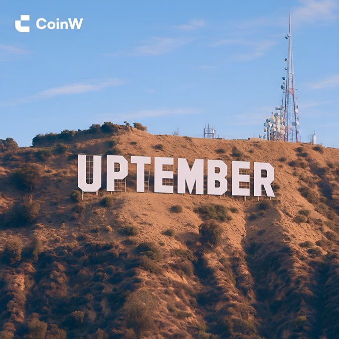The Hollywood sign on a hillside altered to read "UPTEMBER", with a CoinW logo in the top left corner and broadcast towers on the hill.