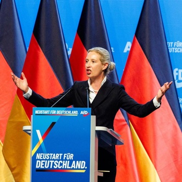 A woman speaking at a podium with 'NEUSTART FÜR DEUTSCHLAND. AfD' branding, gesturing with both hands raised, backed by multiple German flags.