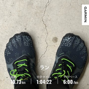 The image shows a person's feet wearing a pair of shoes with green laces, standing on a concrete surface. The shoes are positioned such that they appear to be worn out or damaged, possibly due to excessive use or wear and tear. The photo is taken from an angle where the person's foot can be seen clearly in the foreground while their other foot is partially visible behind them.