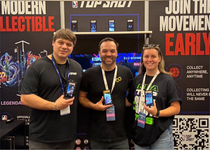 Three people stand at a 'Top Shot' NBA booth, each holding a smartphone displaying the app, with promotional text reading 'MODERN COLLECTIBLE' and 'JOIN THE MOVEMENT EARLY' behind them.
