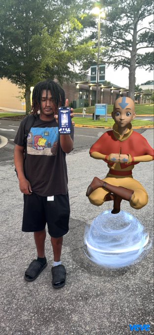 A young person holds up a phone next to a 3D animated avatar of Aang from Avatar: The Last Airbender, who appears to be meditating in a glowing swirl, in what looks like an AR Snapchat filter.