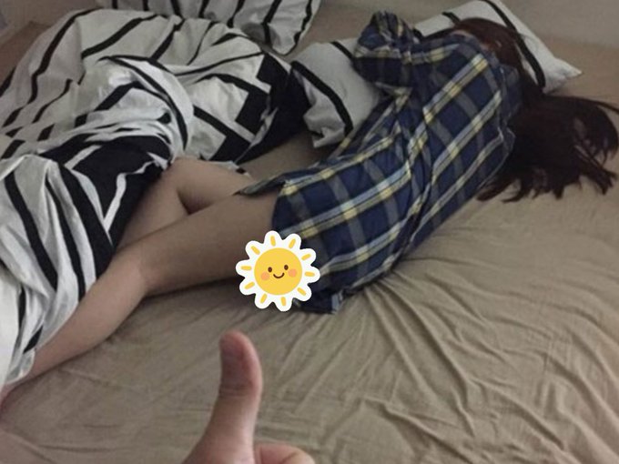 A person in a plaid shirt lies face-down on a bed, with a sun sticker covering part of their body and a hand giving a thumbs-up in the foreground.