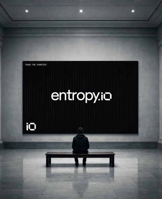 A person sits on a bench in a minimalist gallery space, looking at a large black wall display reading 'entropy.io' and 'TRADE THE FRONTIER.'