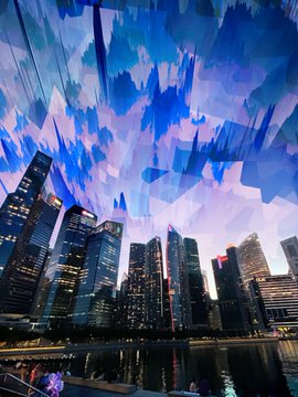 A nighttime cityscape of skyscrapers reflected in water, overlaid with abstract blue and pink digital paint strokes.