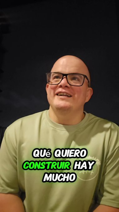 A bald man with glasses smiles while wearing a light green t-shirt, with Spanish text overlay reading 'QUÉ QUIERO CONSTRUIR HAY MUCHO'.