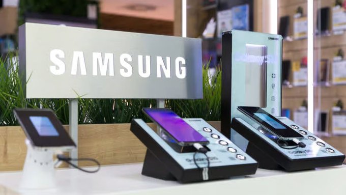 A Samsung store display showcasing the company name in white letters alongside various smartphones on display stands.
