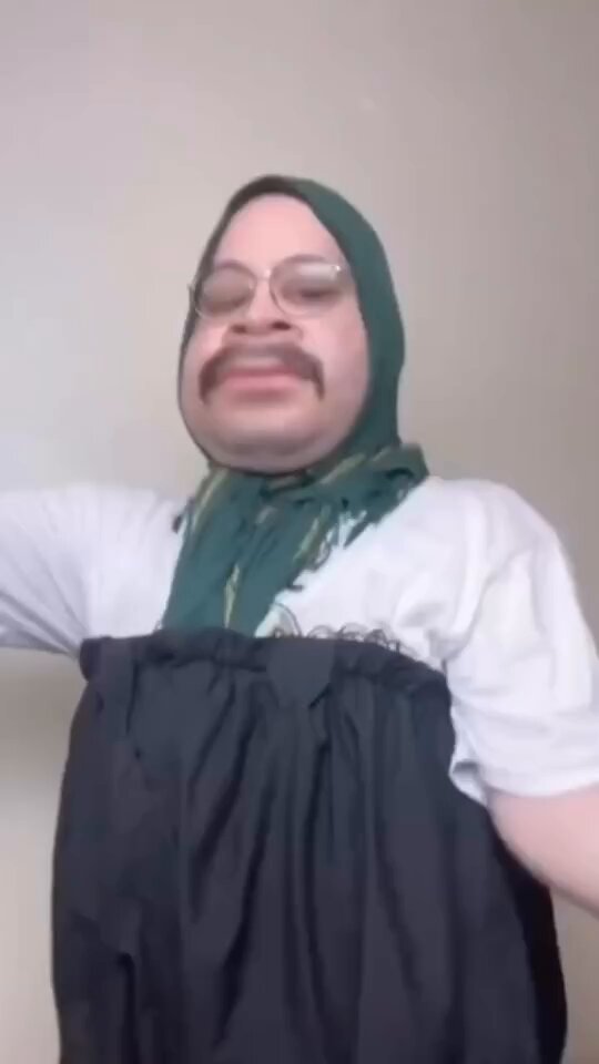 The image features a man wearing a black dress, with his arms outstretched as if he's about to hug someone or something. He has a mustache and glasses, giving him a unique appearance. The caption of the image reads "Thanks wallchain for changing lives", which suggests that the man in the picture is promoting an organization called Wallchain, which provides essential items like clothing to those in need.