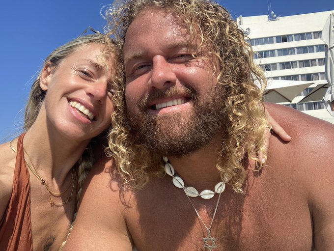 A smiling couple poses for a selfie in beach attire, with the woman wearing delicate gold necklaces and the man sporting a cowrie shell necklace with a Star of David pendant. The image pairs with the post's "Jews for Monero" and crypto-related hashtags, suggesting a personal beach vacation photo shared within a cryptocurrency community.