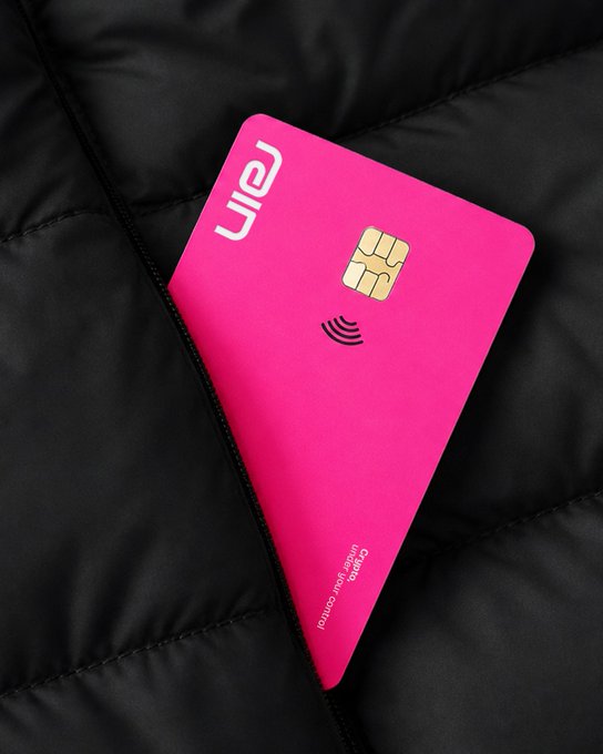 A bright pink credit card partially tucked into a black puffer jacket pocket, featuring a chip and contactless symbol, with text "Cash in when you can't control" near the bottom edge.