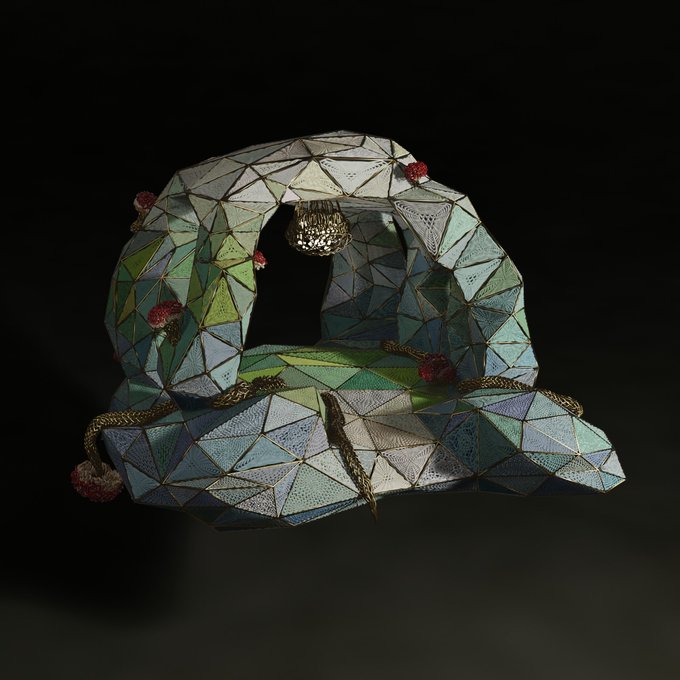The image features a 3D rendering of an intricate piece of jewelry made from small pieces of glass arranged into a geometric pattern, giving it a unique and artistic appearance. The jewelry appears to be a pendant or earring with a triangular design that is composed of numerous smaller triangles, creating a visually striking effect. The background color of the image is black, which contrasts with the vibrant colors of the glasswork and draws attention to the piece. The post also mentions that this particular piece of art has been shared on social media platforms like Instagram or Facebook, indicating its popularity among users.