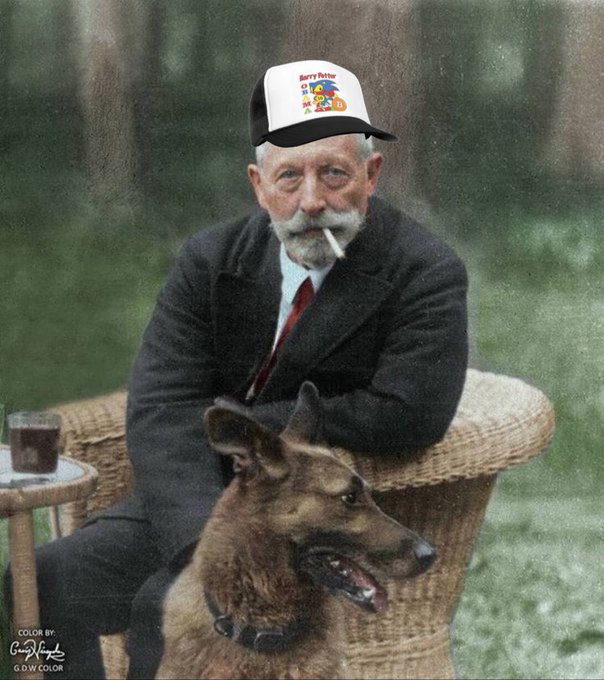 A colorized historical photo shows an elderly man with a white beard wearing a 'Berry Patch' cap, sitting in a wicker chair with a German Shepherd beside him.