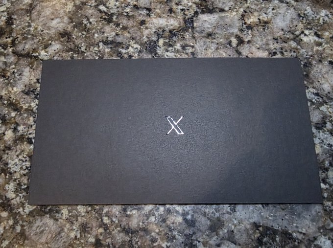 A matte black card with a minimalist 'X' logo in the center, resting on a granite countertop.
