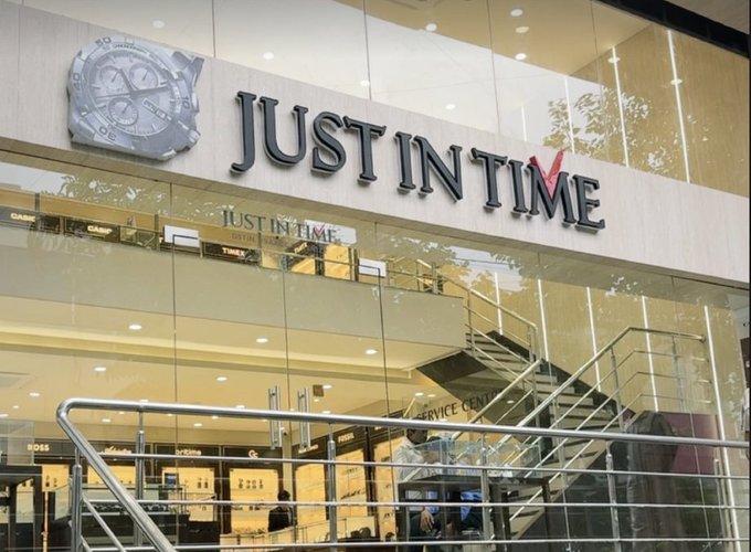 The exterior storefront of a watch retailer called "JUST IN TIME," featuring a large clock logo above the entrance.