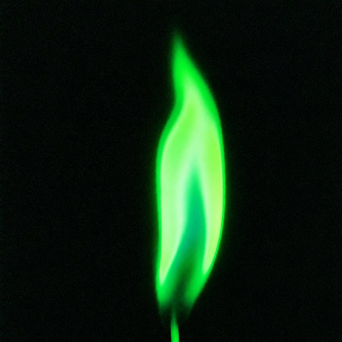 A glowing green flame-like shape illuminated against a black background.