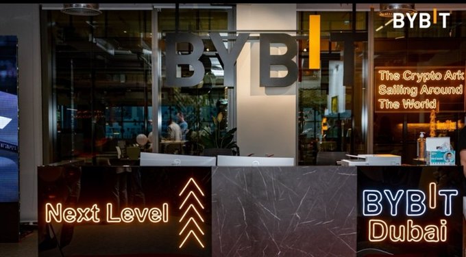 Photograph of the BYBIT cryptocurrency exchange office featuring neon signage that reads 'BYBIT', 'Next Level', and 'BYBIT Dubai' alongside a window decal stating 'The Crypto Ark Sailing Around The World'.