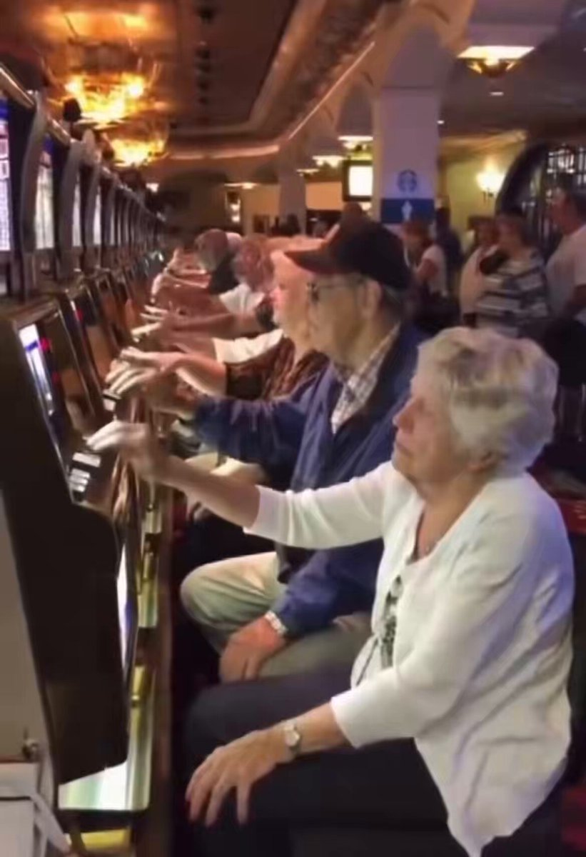 The image features a group of elderly people playing a slot machine, as they each attempt to hit the "buy" button with their coins, potentially aiming for $XRP holders. The photo captures multiple individuals engaging in this recreational activity while standing at different positions around the casino room.