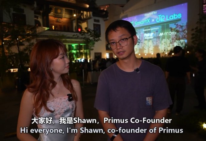 Two people being interviewed at a SmartX x OK Labs event, with the man introducing himself in subtitles as 'Hi everyone, I'm Shawn, co-founder of Primus' (大家好，我是Shawn, Primus Co-Founder).