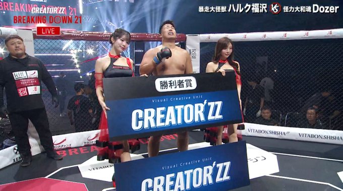 The image shows a post-fight scene from "BREAKING DOWN 21" (Live broadcast), featuring fighter Hulk Fukuzawa (ハルク福沢) receiving the winner's prize (勝者賞) sponsored by "CREATOR'ZZ" as the "Visual Creative Unit." He stands shirtless in the center of the octagon wearing blue MMA gloves, flanked by two ring girls in red and black outfits holding the oversized CREATOR'ZZ check. The top banner indicates his full-mark unanimous decision victory over Dozer (ドーザー 怪力大和澤), matching the post about his decisive win.