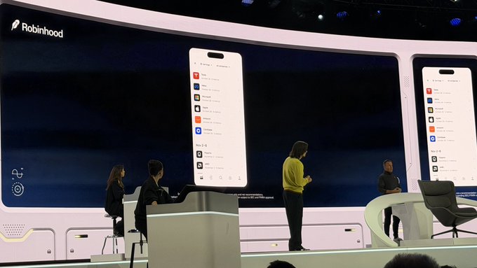A Robinhood presentation on stage shows a large display of the mobile app interface, with several presenters standing on the demonstration platform.