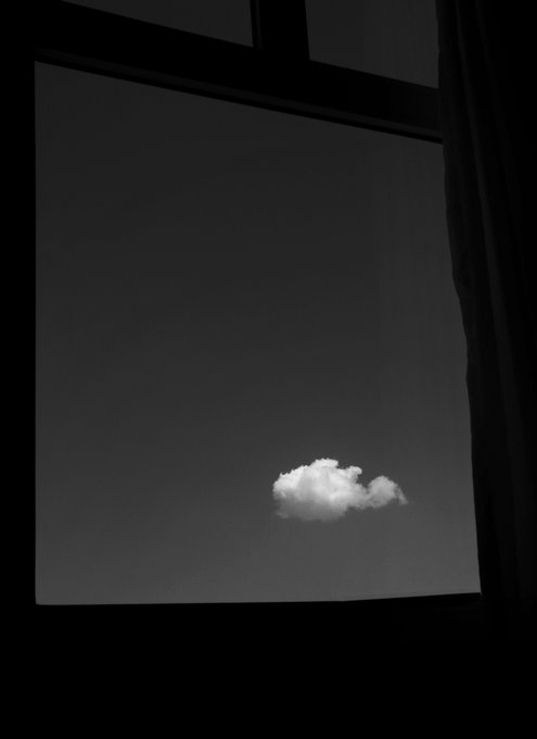 A minimalist black-and-white photograph of a single white cloud viewed through a large, dark-framed window.