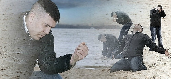 A composite/montage image shows a man in the foreground with his head bowed, while the background depicts several people in black jackets kneeling and praying on a sandy beach.