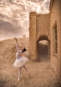 A surreal photo of a ballerina in a white tutu dancing among ancient desert ruins under a dramatic cloudy sky.