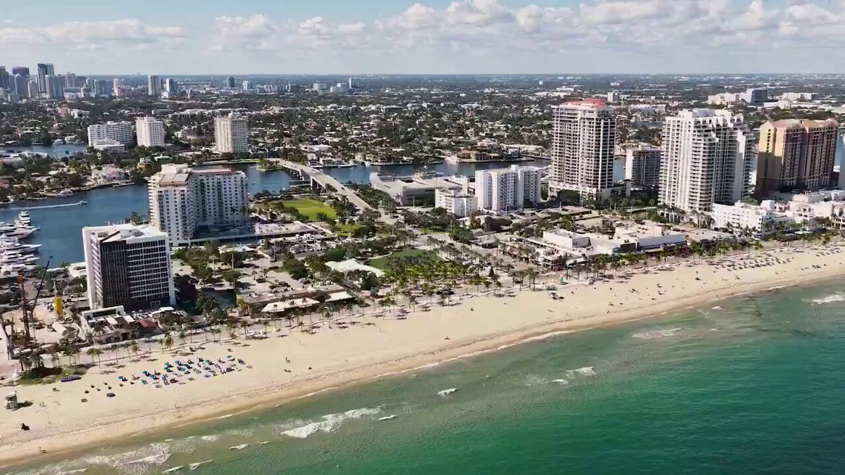 The image shows an aerial view of a beachfront city with tall buildings, including hotels and apartment buildings, along the shoreline. The ocean can be seen in the background, adding to the scenic beauty of the scene. The photo also features a watermark that reads "Say goodbye to waiting days for cross-border funds". This suggests that there might be an online platform or service available for international money transfers, potentially offering faster and more convenient options compared to traditional methods.