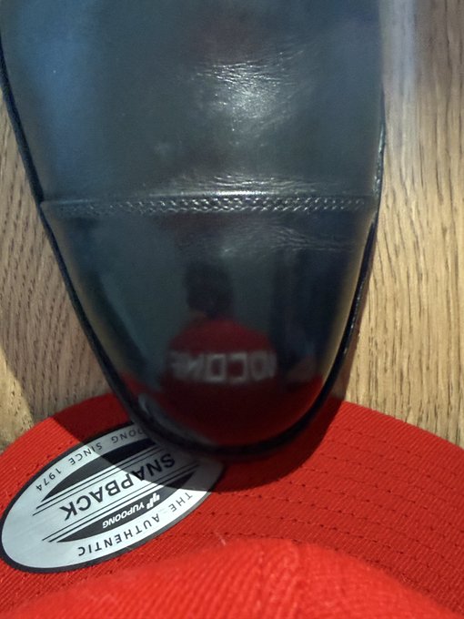 A polished black shoe is displayed on its side, revealing its red SnapBack flip-flop-style sole and an oval SnapBack label reading "THE AUTHENTIC FLIP FLOPONG (sic) SNAPBACK DONG SINCE 1974," with a reflection of "10 CDRI" visible in the glossy upper—prepped and ready for the BTC Treasuries conference in NYC.