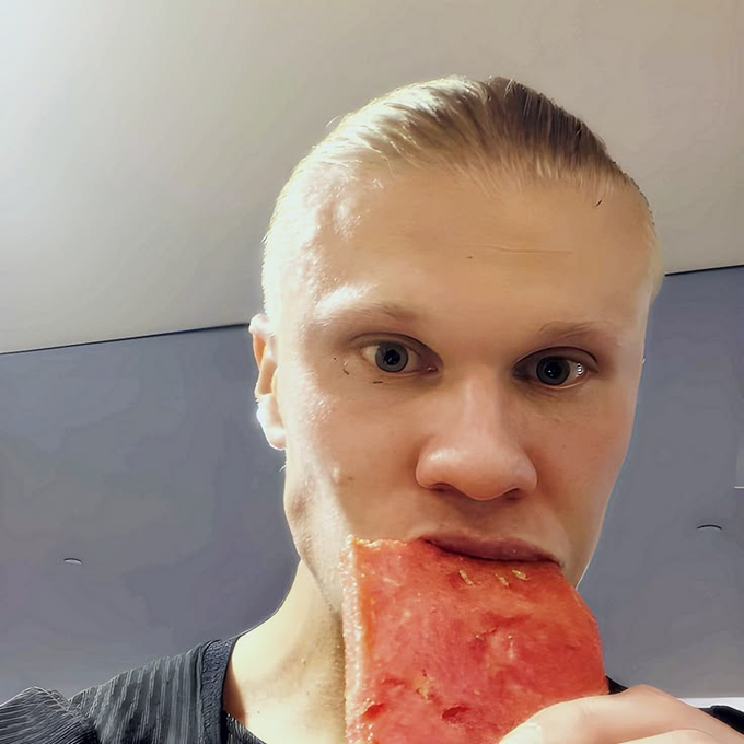 A close-up selfie shows a man with slicked-back blonde hair biting into a red popsicle or frozen treat.