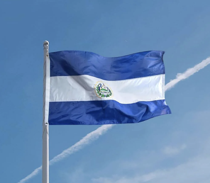 The flag of El Salvador waves against a clear blue sky, symbolizing the nation that continues to expand its Strategic Bitcoin Reserve with its latest acquisition, bringing its total holdings to 7,762 BTC.
