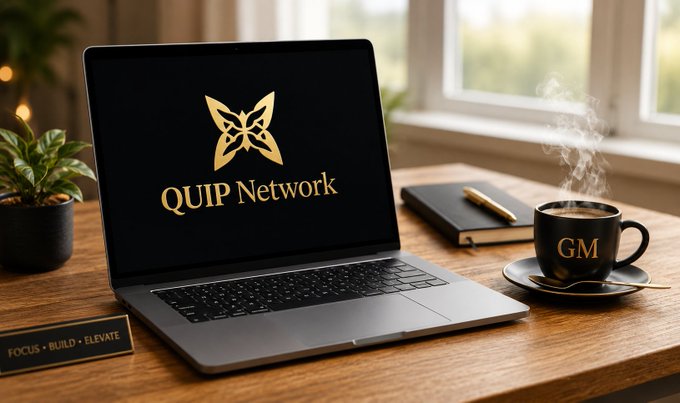 The image features an open laptop computer sitting on top of a wooden desk with a black coffee cup nearby. The laptop screen displays the Quip Network logo, which reads "quip network", along with the phrase "focus on what is in the image". This suggests that the image might be related to the Quip Network or their focus on developing and testing new security systems.