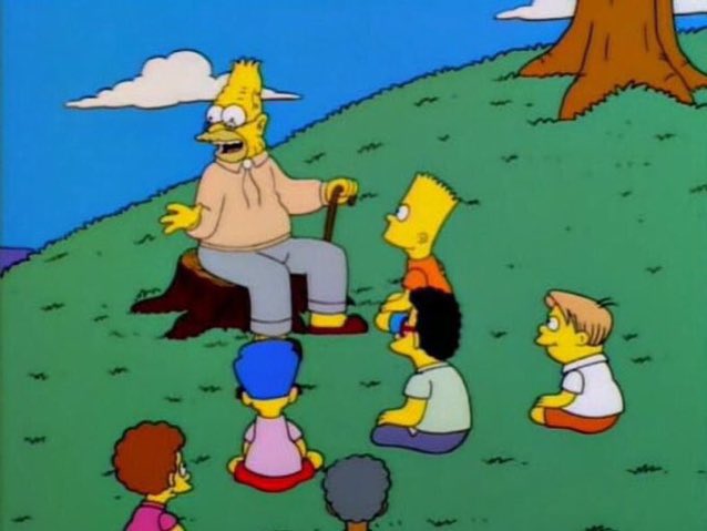 The image shows an elderly character from The Simpsons sitting on a tree stump, telling stories to a group of attentive children seated on the grass. The post's caption "back in my days memecoins used to run to billions" humorously frames the scene as the elderly character reminiscing about past crypto market highs to a younger, naive audience.