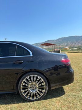 A sleek black luxury sedan parked on grass with mountains in the background, representing the tangible rewards of crypto wealth—often used to symbolize success through flashy purchases like cars, watches, and lavish lifestyles.