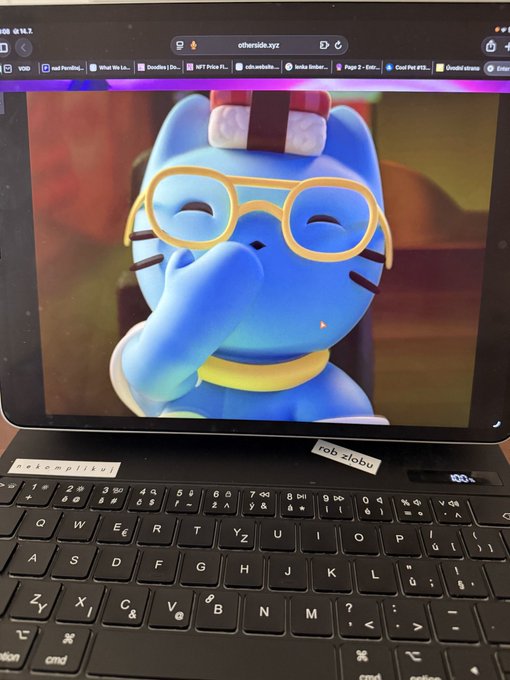A MacBook displaying an image of a blue cartoon cat character with glasses, with stickers on the laptop reading 'palemoliku' and 'reb zloba', showing the URL 'otherside.xyz' in the browser.
