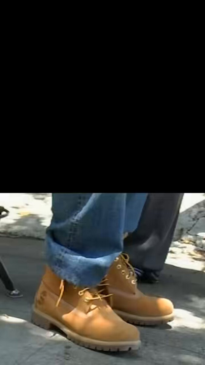 The image shows a pair of tan boots with yellow laces, positioned on someone's feet while they are standing on a sidewalk or street. There is also a black background visible in the photo. The caption "Only Possible On Solana" appears next to the boot image, which might be related to a specific location or event.