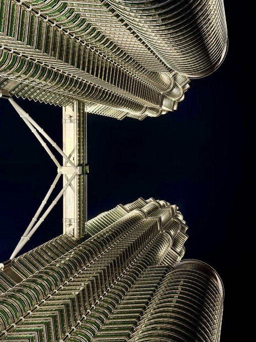 A close-up, low-angle view of the Petronas Twin Towers against a dark sky, showing the intricate architectural details and connecting bridge. The image serves as a striking visual backdrop to the post's discussion about Bitcoin and MSTR price predictions, though the towering structures metaphorically reflect the author's perspective on potential market support levels around $45k for Bitcoin and $40 for MSTR.