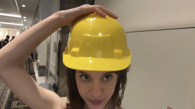 The image features a woman wearing a yellow hard hat, posing for a photo. The caption of the image reads "finally, Build on Stellar Hackathon kicked off with @BuildOnStellar and @riseinweb3 teams. who’s coming?". This suggests that the post is related to an event or competition involving the use of hard hats by two teams from different companies.