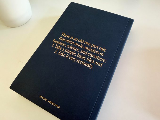 A navy blue notebook with gold text quoting a 'two-part rule' from 'STRIPE. PRESS//PCA', advising to 'Take a simple, basic idea and take it very seriously.'