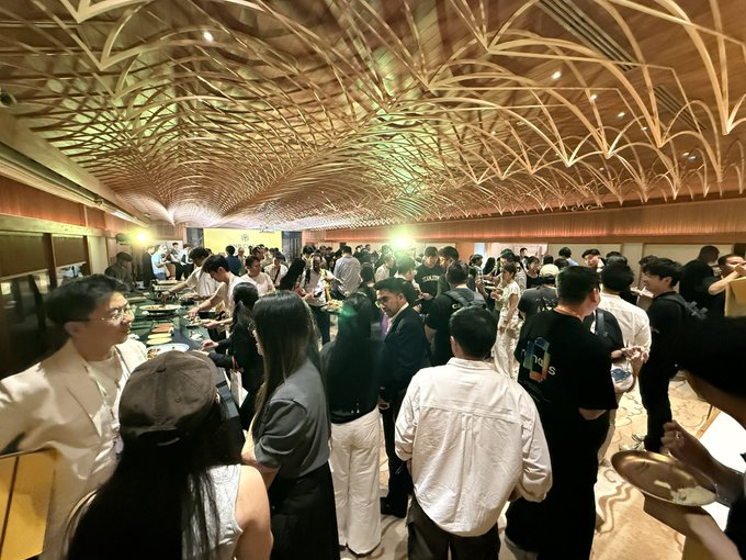 A crowded networking event takes place in an elegant venue featuring a striking wooden lattice ceiling, with attendees mingling around food stations in what appears to be a side event at WebX Asia hosted by BNB Chain.

The image aligns with the post by capturing the lively atmosphere of the WebX Asia side event sponsored by BNB Chain, showing a packed room of attendees networking and enjoying refreshments beneath the venue's ornate architectural ceiling.