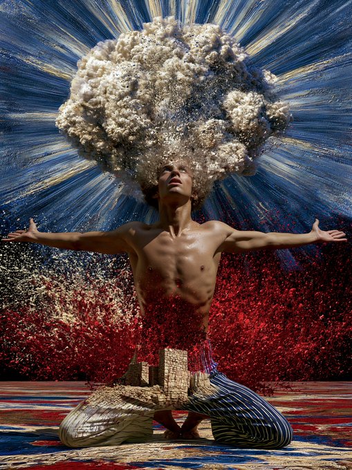 Surreal artwork of a kneeling shirtless figure with a mushroom cloud explosion emerging from where their head should be, with red particles spraying outward.