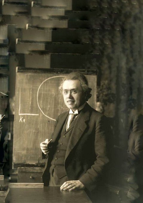 The image shows a professor standing at a chalkboard with a drawn circle and the letters "Kr" visible, in what appears to be a vintage sepia-toned classroom setting. The caption likely draws a playful parallel between this academic figure teaching foundational concepts and CZ (Changpeng Zhao), the founder of Binance, who once guided the cryptocurrency industry, with the chalkboard suggesting early "lessons" that shaped the space he helped build.