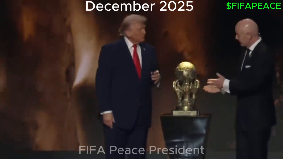 The image features two men standing next to a trophy, with one man wearing a suit and tie while the other has his hands together. The trophy appears to be a gold statue of a person holding a globe or ball. The background shows a dark setting, which could be a stage for an event related to the World Cup. The image also includes text that reads "December 25" and "$FIFAAPEACE", possibly indicating the date of the event or the amount of money involved in it.