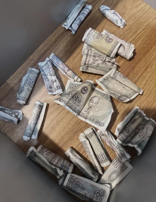 Indian rupee banknotes, including 100 and 500 denominations, are scattered and rolled up on a wooden table.