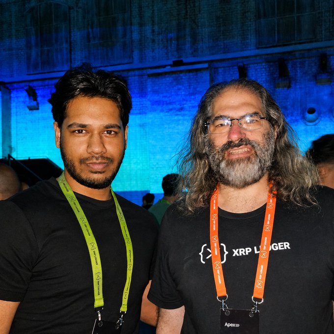 Two men pose together at what appears to be a crypto/blockchain conference, both wearing lanyards—one with an "X" symbol (Xpring) and the other featuring "XRP Ledger" branding on the t-shirt—supporting the post's claim about collectively owning over 1 billion $XRP, with the man on the right identified as Ripple CTO David Schwartz.
