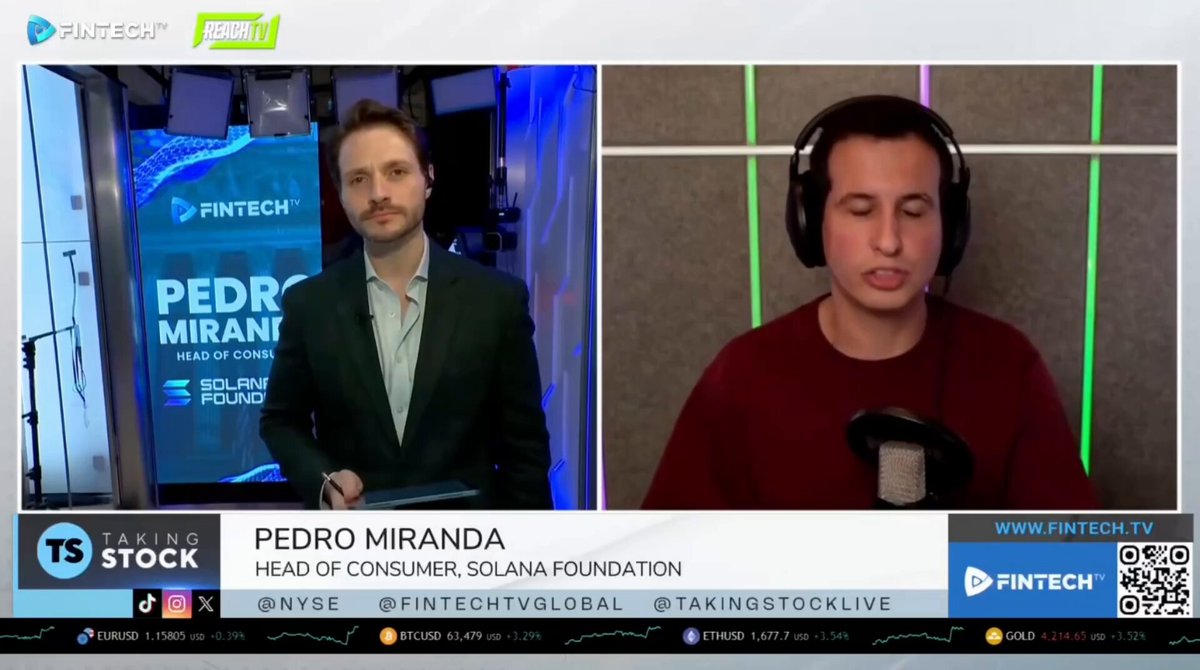 The image shows two men wearing headphones, with one man standing behind the other who appears to be speaking into a microphone or headset. The background of the image features a news broadcast screen displaying information about tokenized shares from the company SpaceX on Solana. The text in the image suggests that these tokenized shares are launching on Solana and can be accessed by anyone with a Solana wallet, making it an accessible investment opportunity for a global audience.