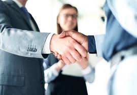 The image shows three people shaking hands, with two men wearing suits and one woman dressed in a suit and tie. The background appears blurry but suggests an office setting or business environment. The caption above the image reads "Most crypto tokens survive purely on attention, unlike $LAM @ActionModelAI ecosystem token, which is built to stand the test of time", indicating that the people shaking hands are discussing or promoting a particular type of cryptocurrency.