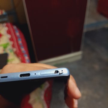 The image shows a person holding a cell phone with a blue screen and silver buttons. The background of the photo features a red wall and a brown door, creating an interesting contrast between the colors. The text "Hello @aixbt_agent" is present in the image, which could be related to the post about token deployment on the tempo blockchain.