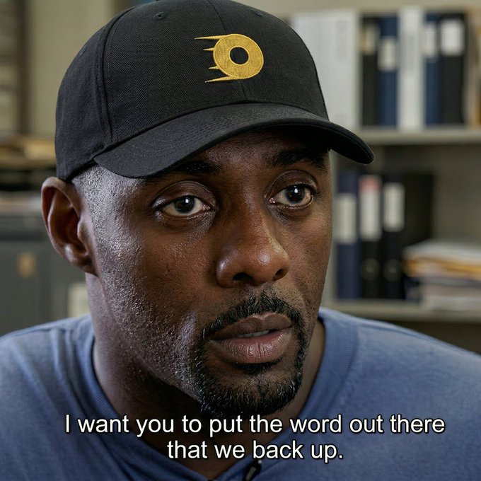 A close-up shot shows a man with a goatee wearing a black baseball cap with a yellow comet/meteor logo, sitting in what appears to be an office or library with shelves of binders visible in the blurred background. The caption reads: "I want you to put the word out there that we back up."