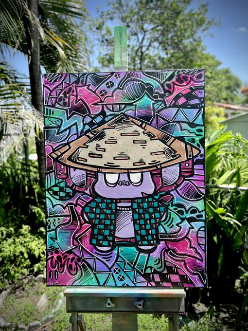 A vibrant, graffiti-style painting on a wooden easel depicts a cartoon character with a mushroom-like cap, set against a lush garden backdrop.
